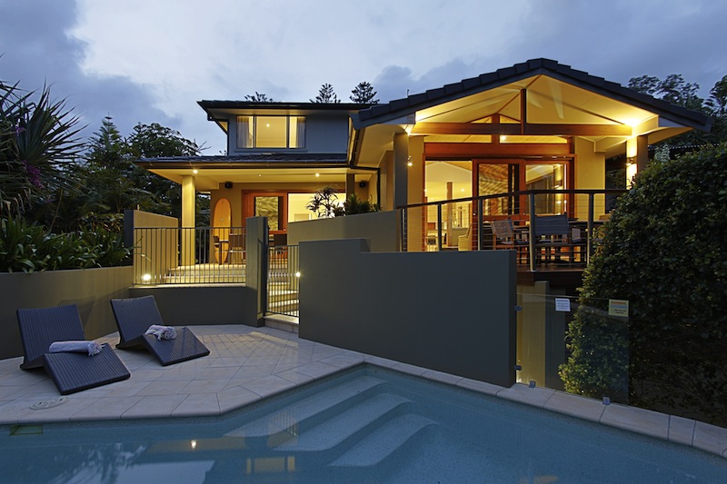 A trendy beach house with a lighted pool is shown.